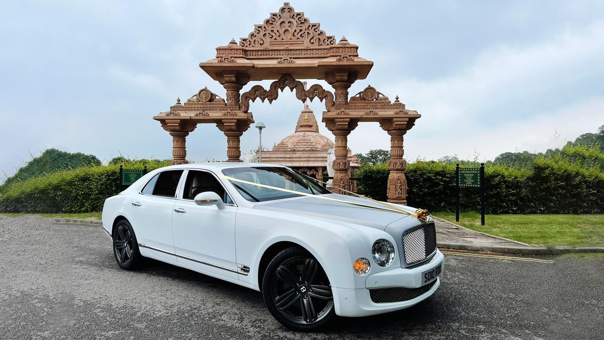 Modern Bentley Mulsanne with Black alloy wheels and Gold ribbons park in front of an Asian Temple in Luton.