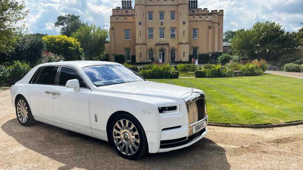 A selection of white Luxurious and modern vehicles all decorated with matching white ribbons on wedding duties in Bath. Frot Left to right: Rolls-Royce Phantom, Rolls-Royce Ghost,