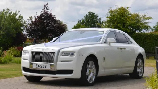 White Rolls-Royce ghost in Derbyshire decorated with white Ribbons entering the wedding venue