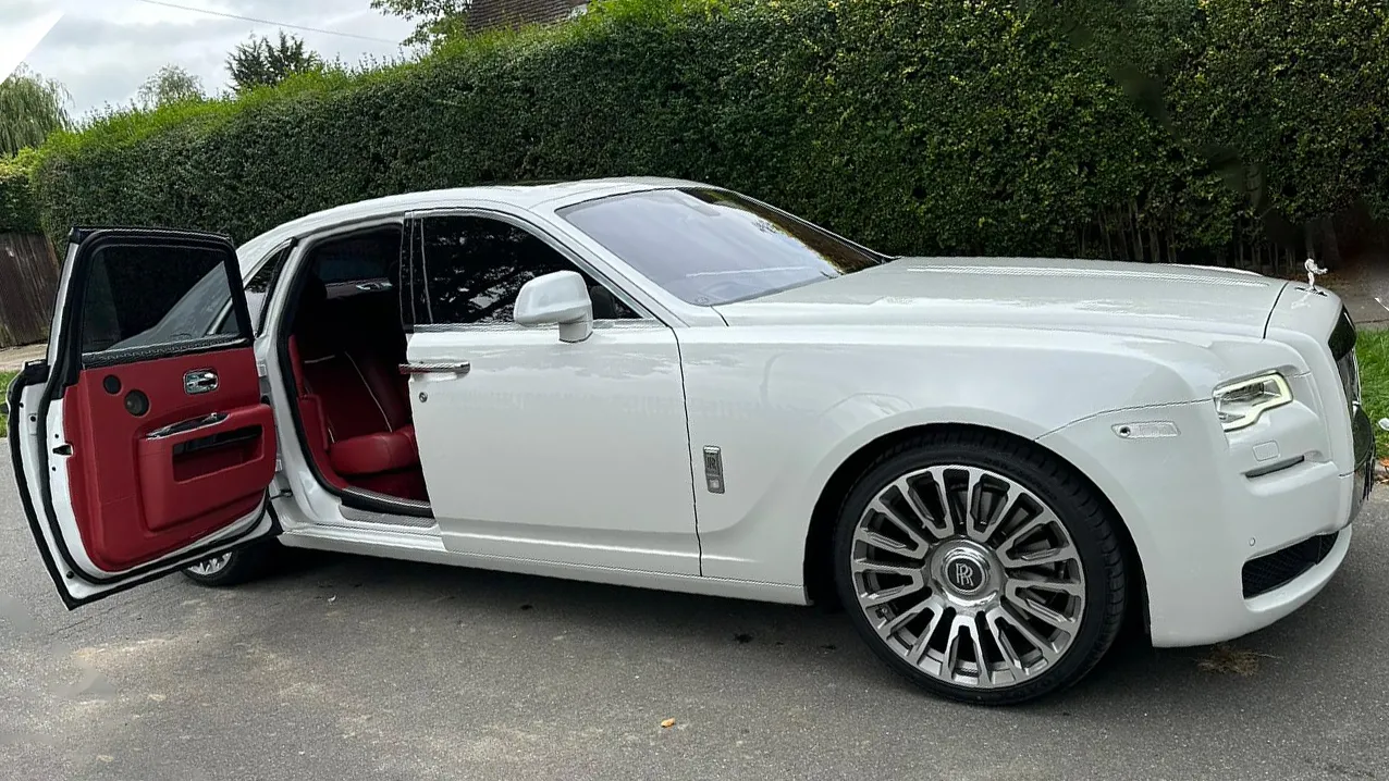 White Rolls-Royce Ghost Series 2 with the rear door open showing a deep burgundy leather interior