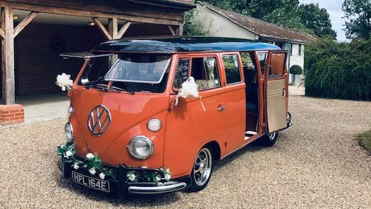 A Vw Campervan in Terracota Orange in front of wedding venue in Woodbridge