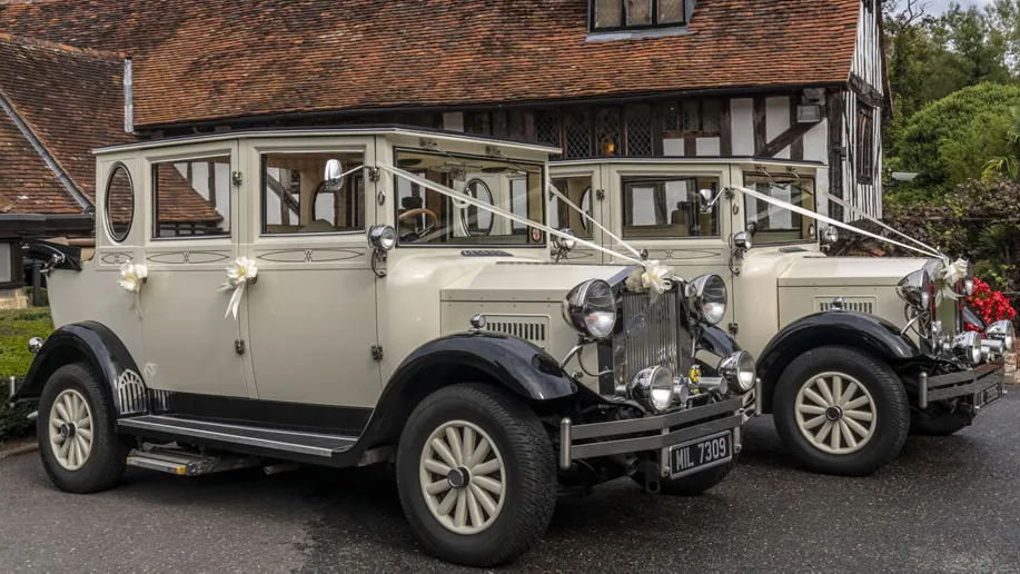 Two identical vintage imperial cars with roof open in front of wedding venue in Bedfield