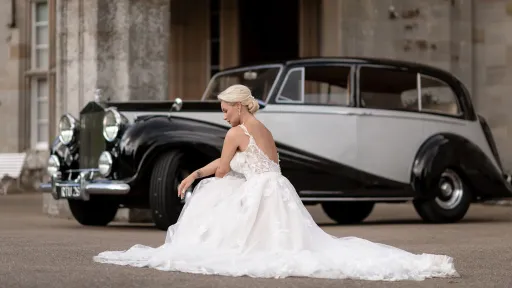 Side View of Classic Rolls-Royce with White Wedding Ribbons driving in street Scottish Highlands.