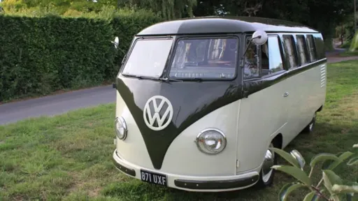 Side view of a Classic Splitscreen Campervan for hire in Devon countryside. The Campervan is White and Dark Green