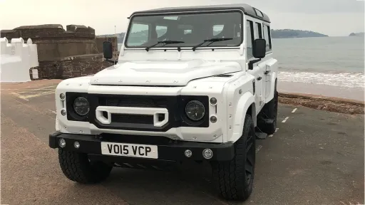 Front View of White Land Rover on Cornwall Beach with Blue Sea at the back