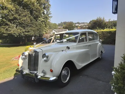 Front side view of classic 7-seater limousine in front of wedding venue in Suffolk decorated with white ribbons