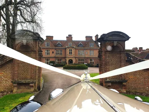 Vintage Wedding Car decorated with White Ribbons entering wedding venue in Bedfordshire. Photo take from the inside cabing looking out to the bonnet of the vehicle