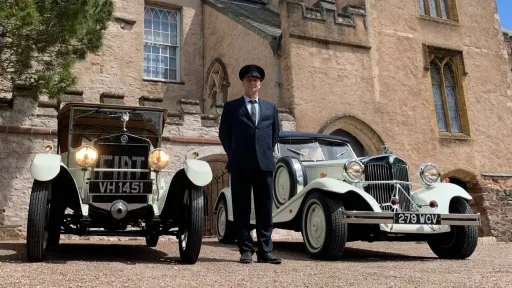 Two White Vintage Cars with their chauffeur standing in the middle. Car on the left is a genuine vintage Fiat and on the right is a 1930's vintage style Beauford. Both are converti