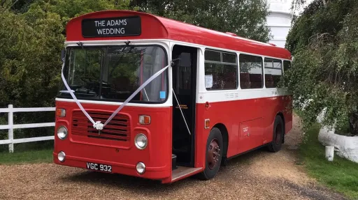 Classic Red Single Decker bus entering Wedding. Bus is decorated with White Ribbons on front grill.