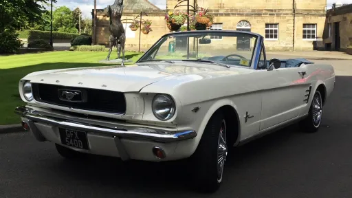 White convertible Mustang Wedding car waiting for married couple to come out of their wedding venue for photos.