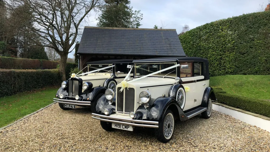 Two Matching Vintage Regent Wedding Car in Black & Ivory dressed with White Ribbons accross the front of the vehicles