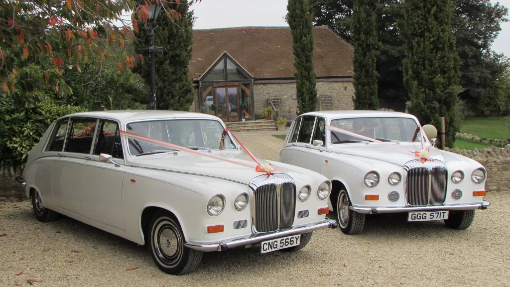 Two Matching 7-seater Classic limousine dressed with matching pink ribbons in front of the wedding venue