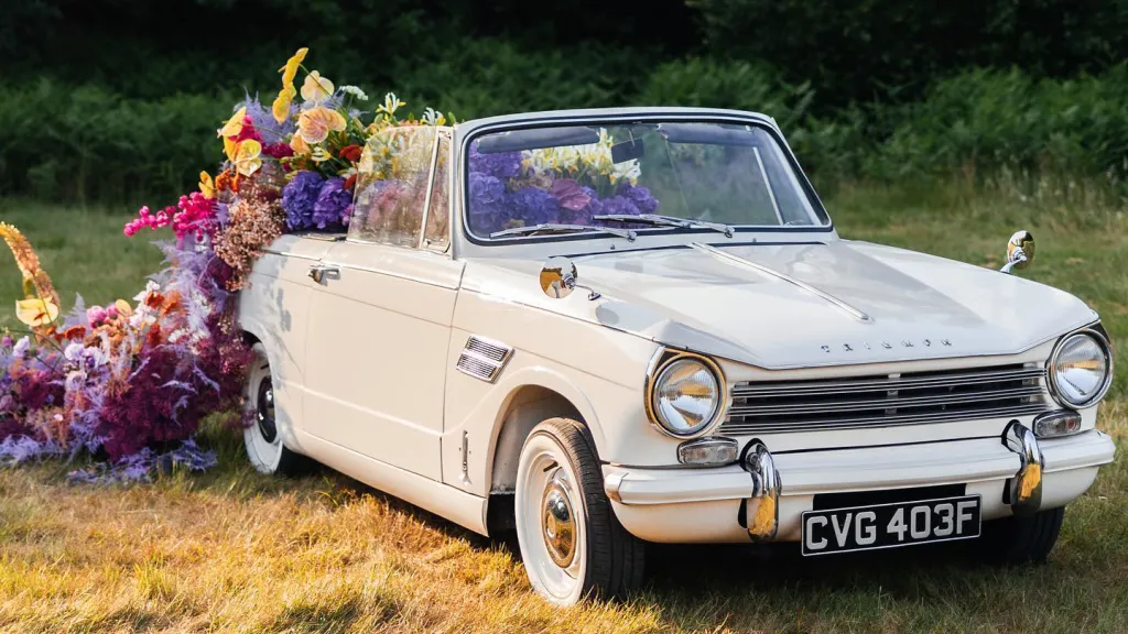 Convertible Triumph decorated with different coloured flower coming out of the rear seats