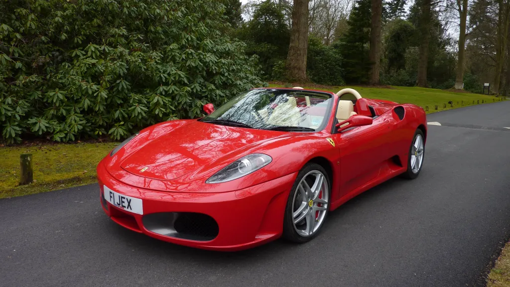 Red Ferrari with convertible roof open showing the cream leather interior