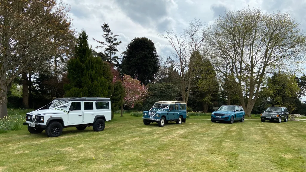 Four land Rover Wedding Cars in a park posing for photos