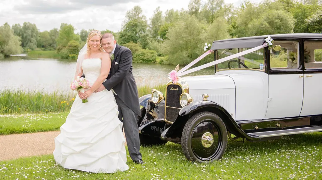 Vintage Black & Ivory Citroen Wedding Car in a park with bride and groom standing in front of the car for photos