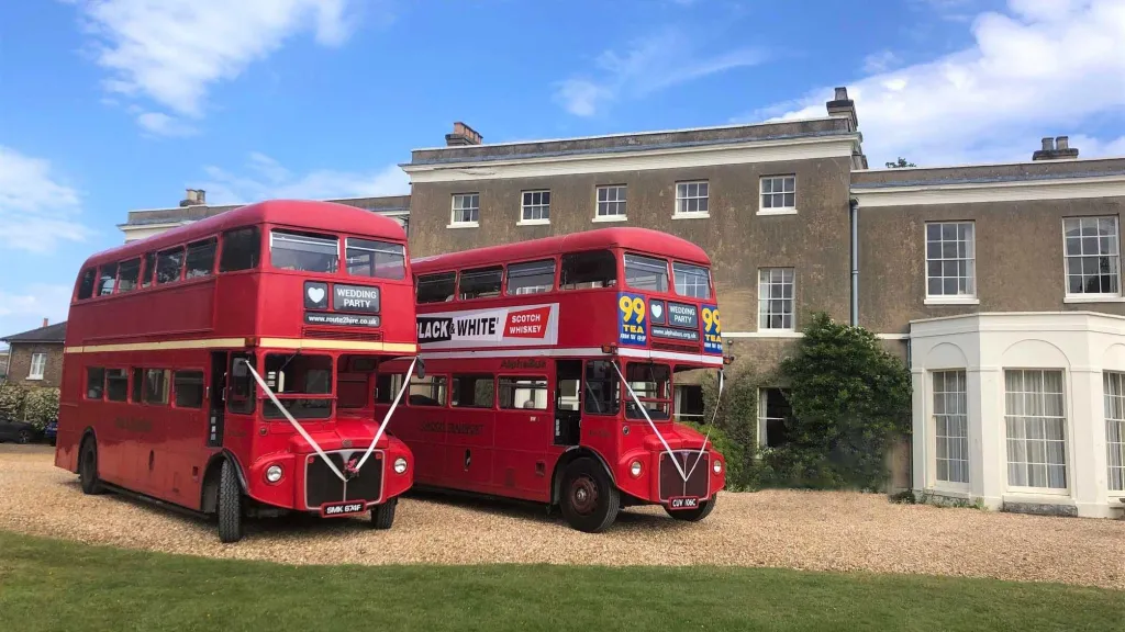 Two Routemaster Bus in front of wedding venue. One of them has vintage advertising on the side