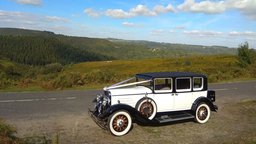 side view of a Vintage Franklin wedding car in top of a cliff with the countryside in the background