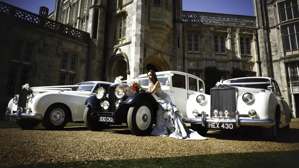 Selection of Classic and Vintage Rolls-Royce aligned in front of wedding venue with Bride wearing in white dress in the Middle of the vehicles
