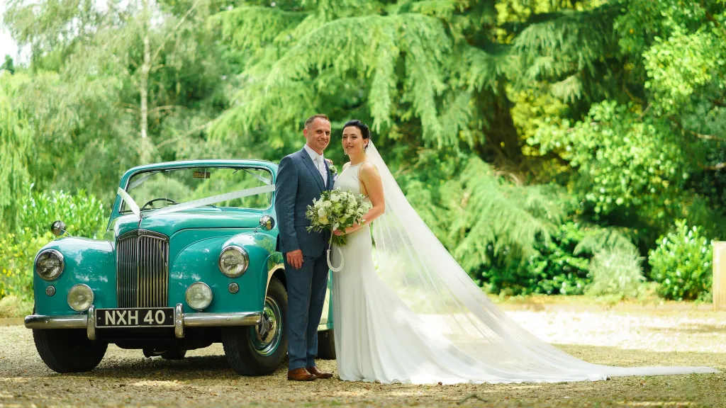 Turquoise Blue Classic Lanchester Convertible With roof open. Bride and Groom standing next to the vehicle