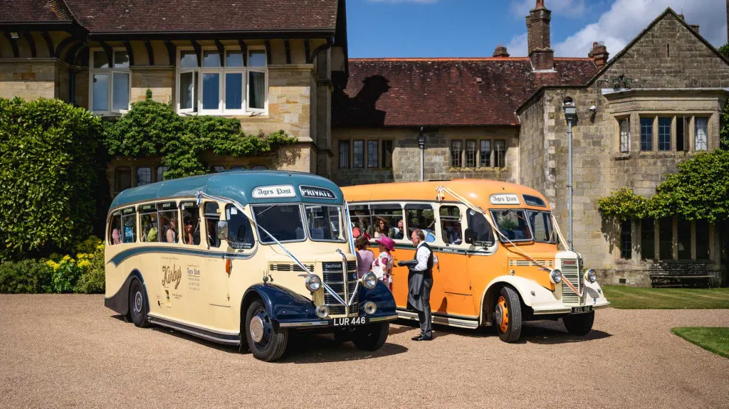 Classic Bedford Buses in front of venue dropping off wedding guests. Both buses are decorated with Ribbons
