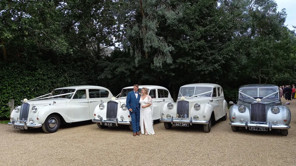 Fleet of four classic Austin Princess Limousines. Birde and Groom are standing in front of the vehicles