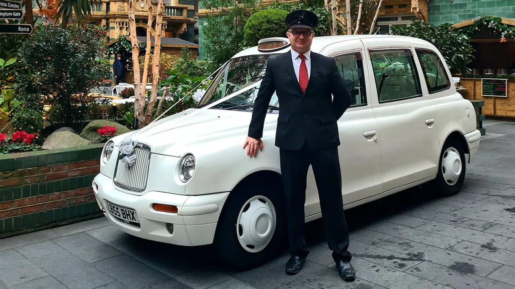 White Modern Taxi with Chauffeur standing in front of the vehicle