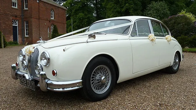 Side view of an ivory Classic Jaguar Mk2 dressed with white ribbons