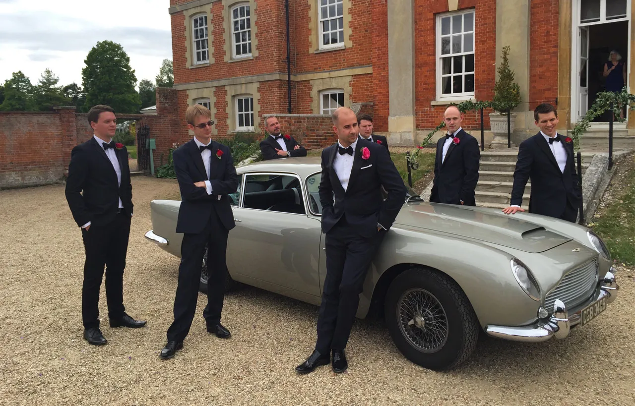 James Bond 007 Aston Martin in Front of wedding venue and Groomsmen wearing matching blue suit posing in front of the car