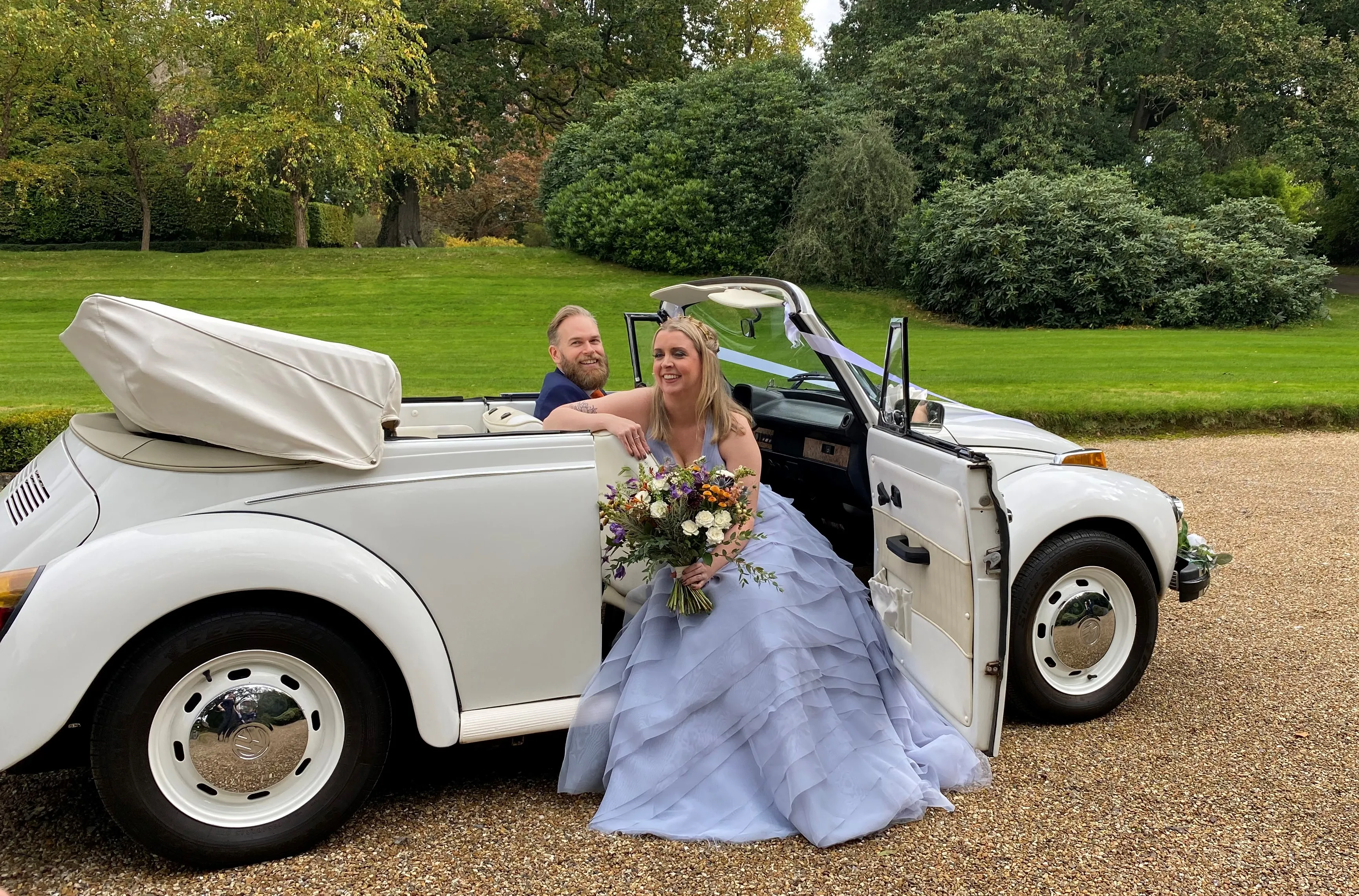 Ivory Classic Beetle Convertible with roof down with bride and groom inside the vehicle.