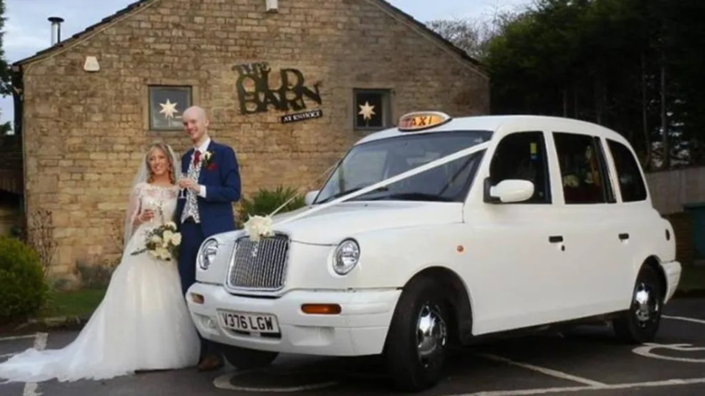 Bride and Groom standing in front of a White Taxi Cab. Traditional "V" shape white ribbon on front bonnet