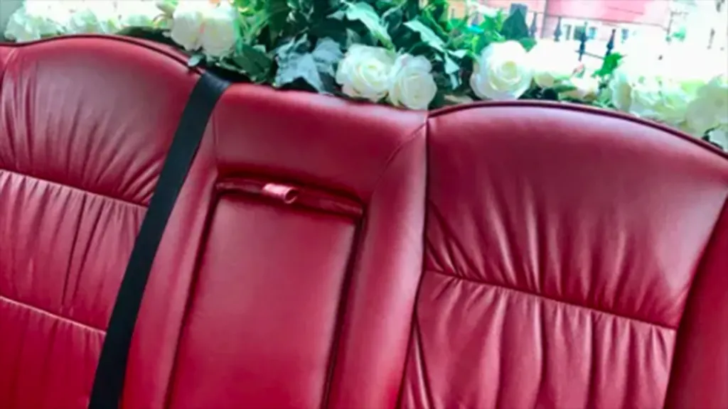 Burgundy Leather interior of the Modern White Cab. Rear parcel shelves white wedding flower decoration are showing on the photo