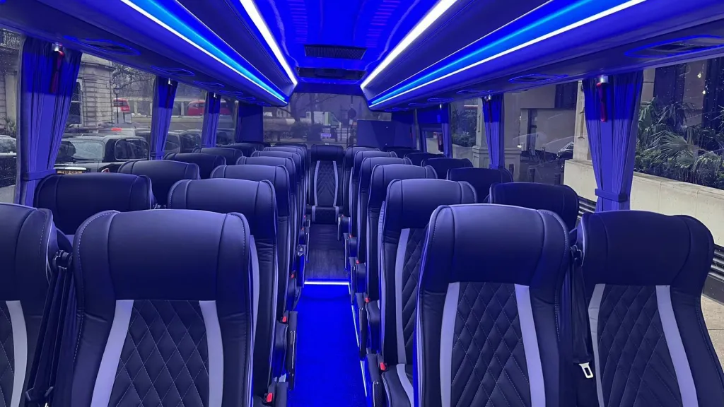 Interior of a 34-seat modern coach showing the Black & Silver Leather seats equipped with seat belts and Blue Neon Light