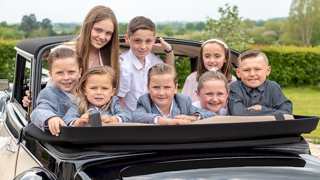 Wedding Page Boys and Flower Girls in the rear of the vehicle with roof down all looking at the photogrpaher
