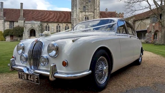 Side view of Classic Jaguar Mk2 with white ribbons in front of a wedding church