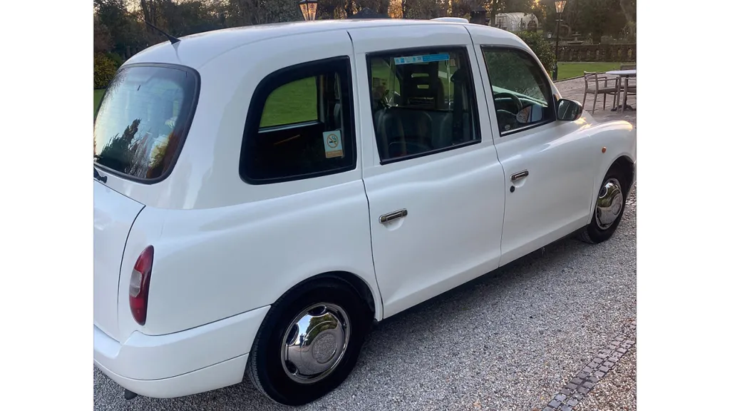 Rear Side view of White taxi cab showing the large side entrance door and Chrome Wheels