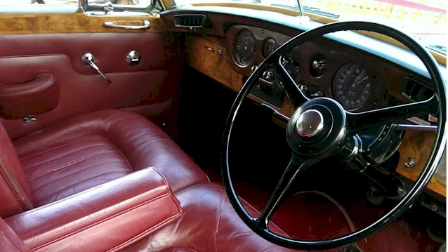 Inside of Classic Bentley Front seat showing the Burgundy leather and Wooden Dashboard.
