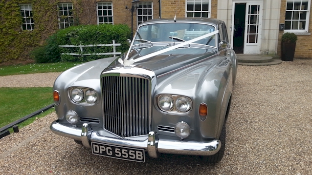 Front view of a Classic Bentley in Silver with white ribbons across its bonnet showing the large Chrome Grill