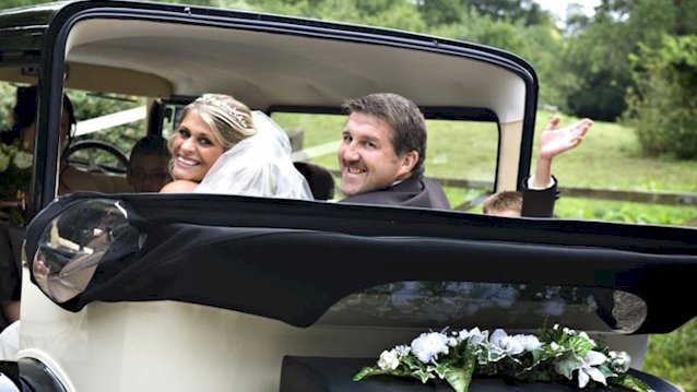 rear view of Bramwith Convertible with roof down, flowers on rear parcel shelf and Bride and Groom inside the vehicle looking backward