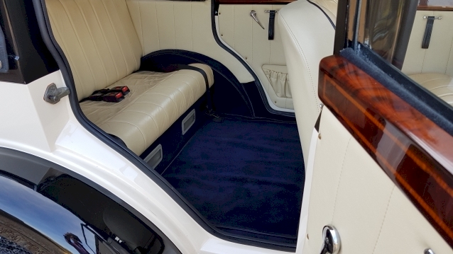 inside rear cabin showing blue carpet, cream leather seats and wood on the doors
