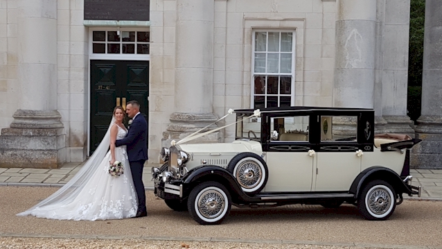 Ivory and Black vintgae car with roof down. Bride and groom in front of the vehicle