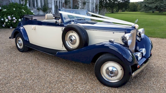 Right side view of Blue and Ivory Convertible Royale Jaguar wedding car with White ribbons accross front bonnet