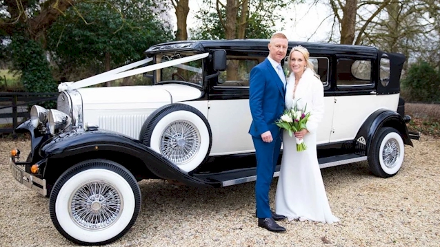 Bride and Groom standing in front of a Black and white vintage wedding car
