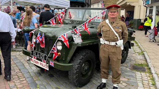 Classic Army Green Austin Champ Jeep decorated with British Flags with its chauffeur wearing a ceremonial period uniform standing at the side of the vehicle