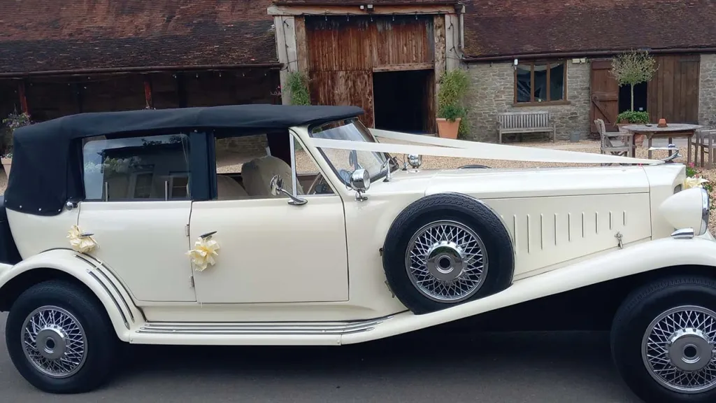 Right Side view of Ivory Beauford with Black Roof up, Spare wheel mounted on right wheel arch and Traditional V-shape white ribbon accross the bonnet