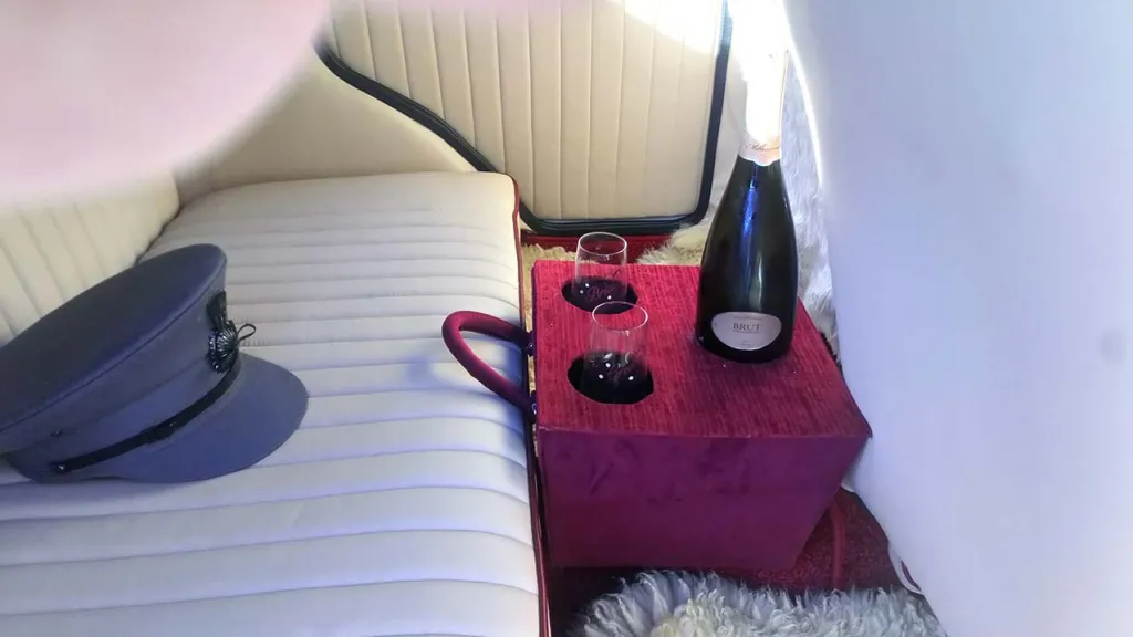 inside rear seating area with chauffur's hat on the rear bench seat,  mini bar in the middle of the seat
