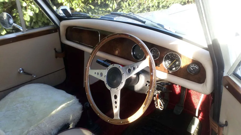 Inside front view of passeger seat, Cream top dashboard with wood in the middle.
