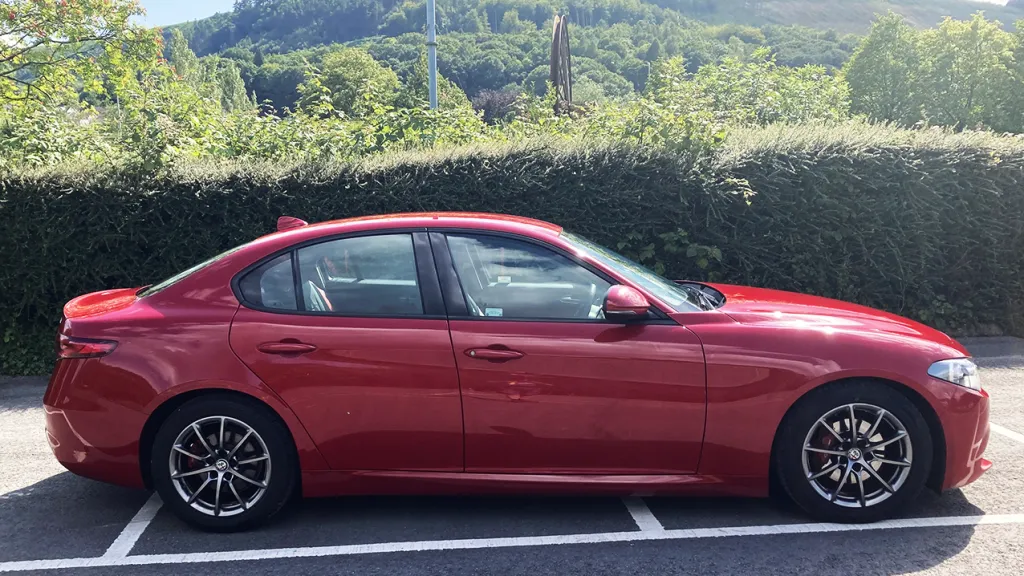 Side View of a modern red Alfa Romeo Giulia with black and silver qlloy wheels