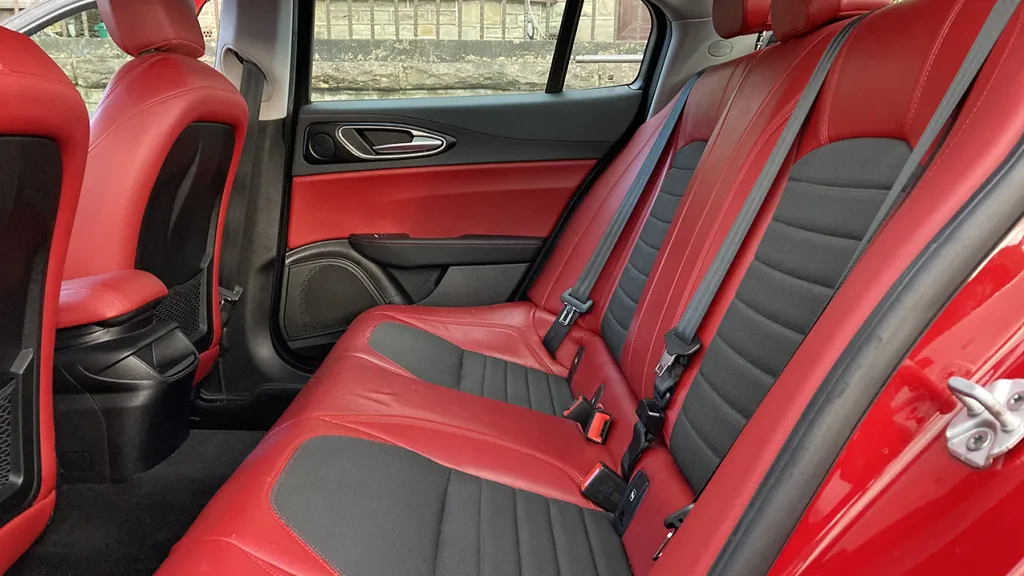 rear interior of a sporty modern Alfa Romeo Giulia. Interior is in leather two-tone red and black