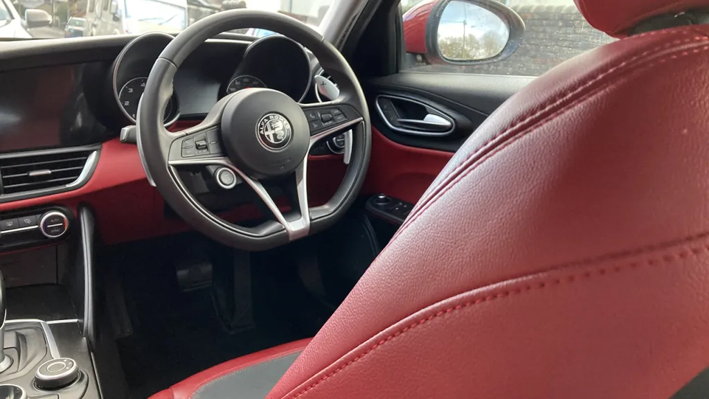 Driver seating area view of Black and Red Dashboard in a Modern Alfa Romeo Giulia